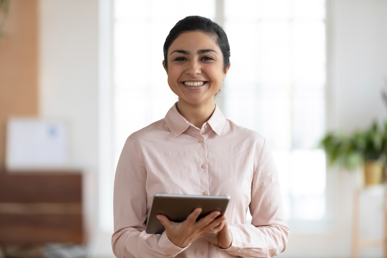Profile picture of smiling indian female employee using tablet